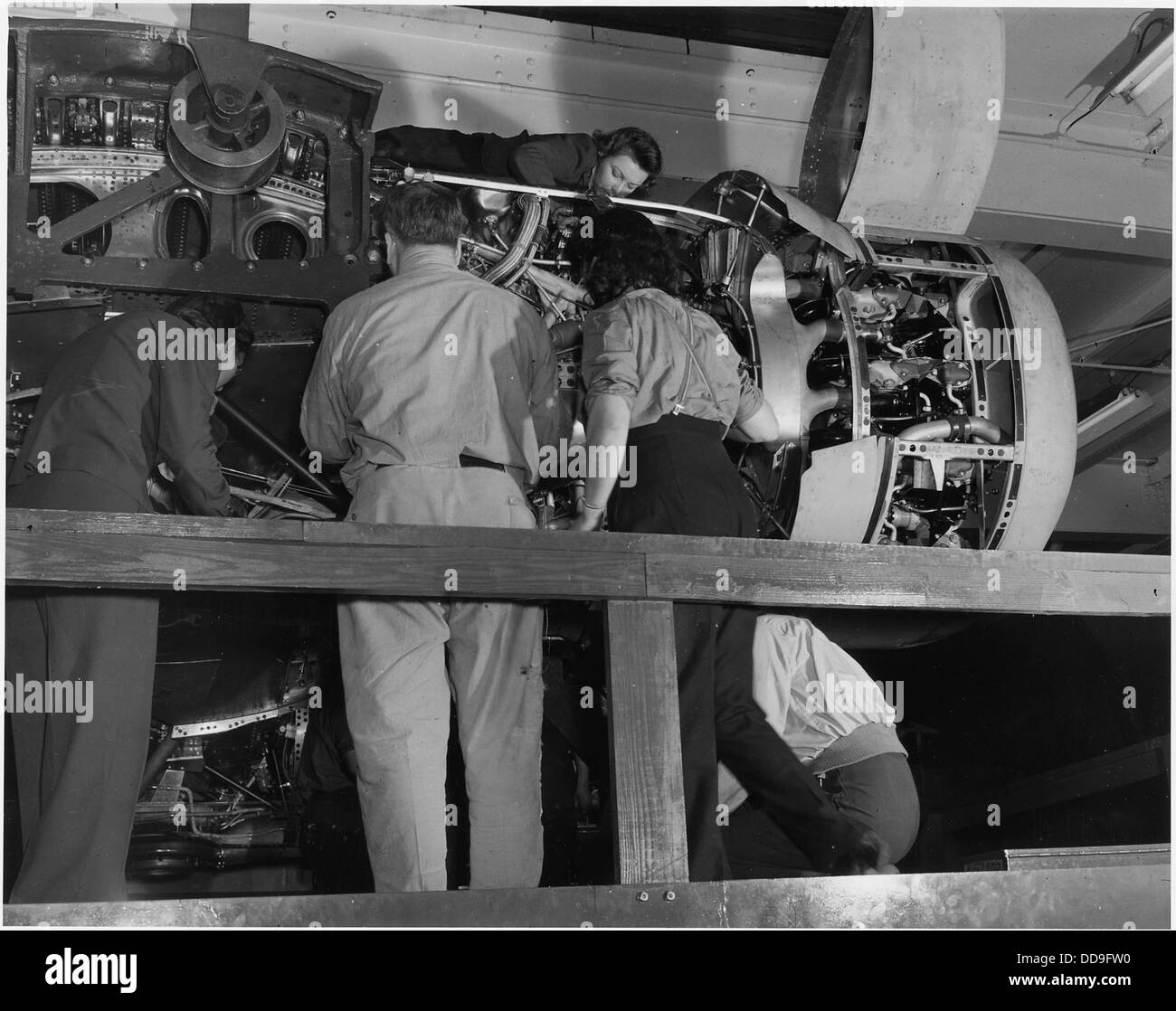Installing one of the four engines of a new B-24E (Liberator) bomber on one of the assembly lines of ford's big... - - 196388 Stock Photo