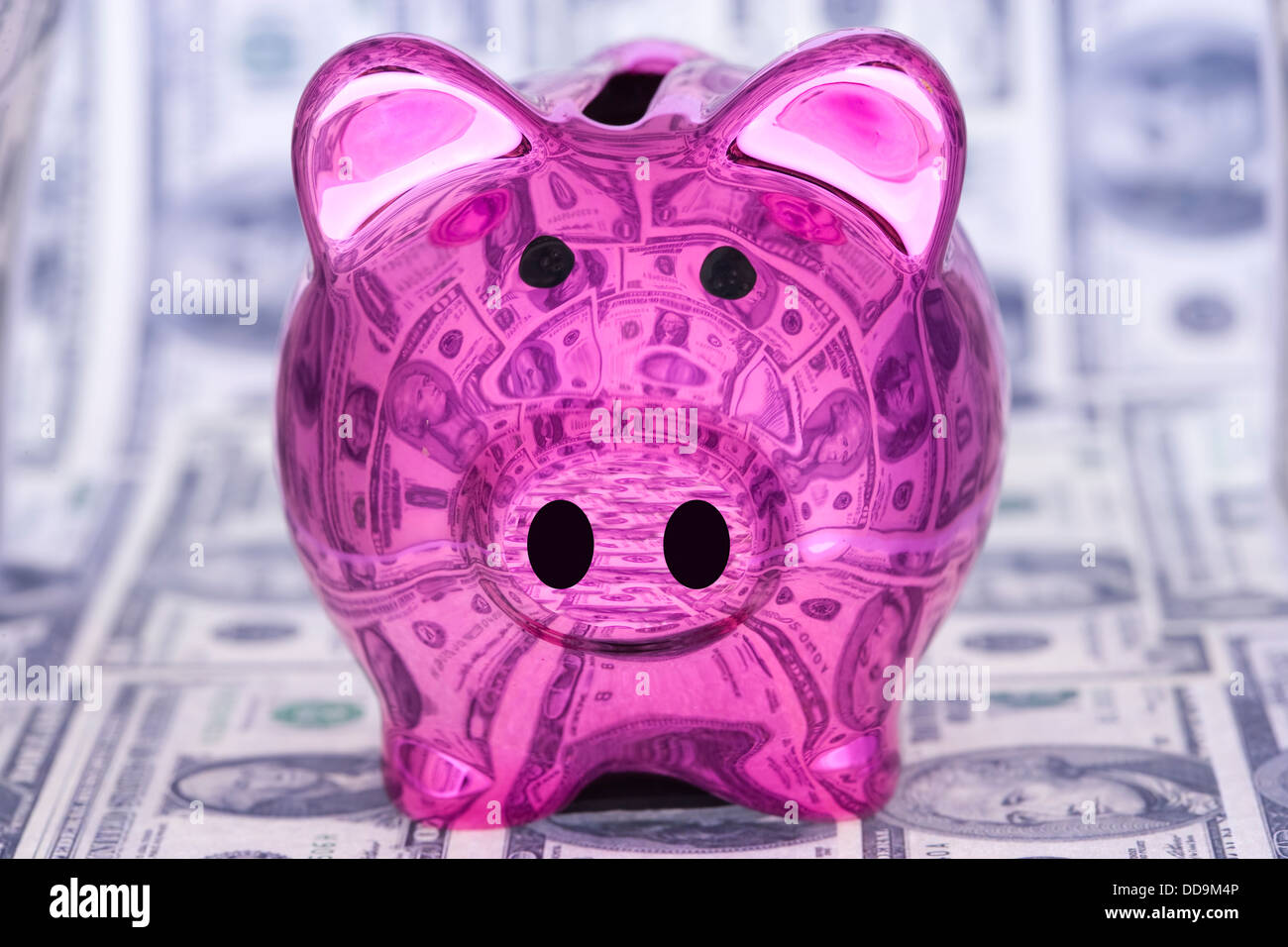 A pink shiny piggy bank surrounded by dollar bills and reflecting them ...