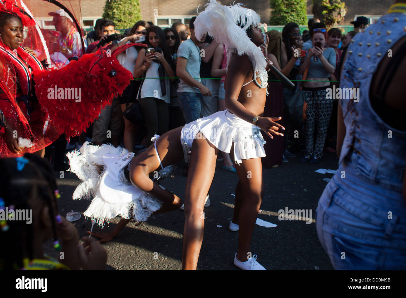 Performers of the Notting Hill Carnival dance bum to bum wearing white costumes to the joy of the spectators. Stock Photo