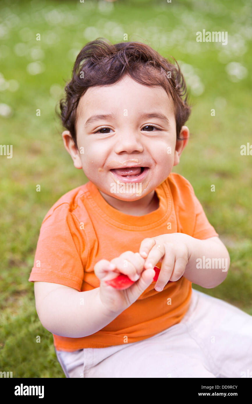 Baby boy holding spoon, smiling Stock Photo