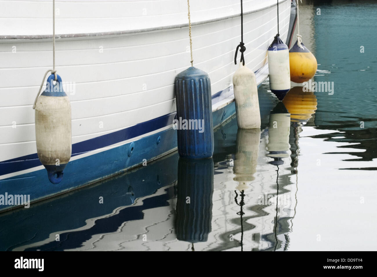 Boat fenders hanging over the side of a boat docked in the harbor at