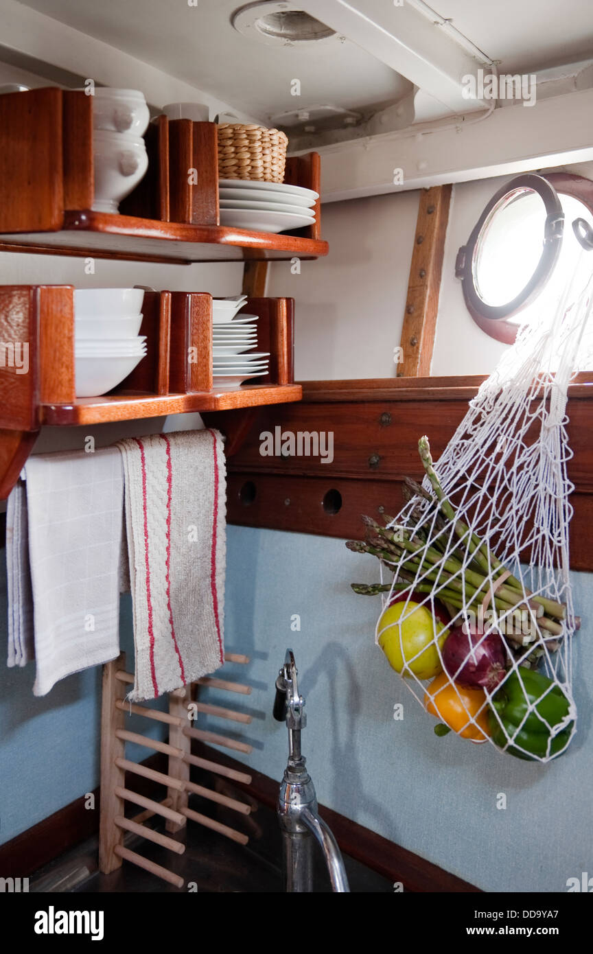 Cabin interior - crockery storage and drawstring bag hanging from porthole window Stock Photo
