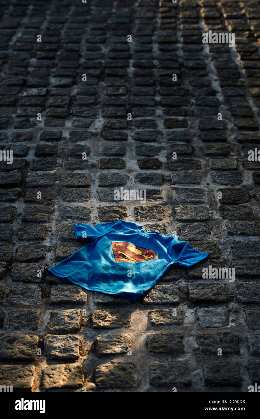 Childs superman t shirt lit by the sun on a cobbled street. UK Stock Photo