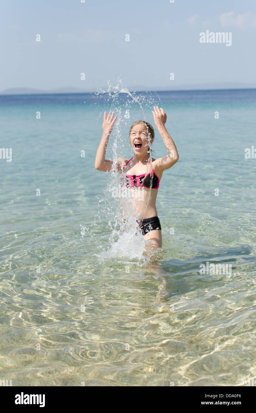 Girl playing in the sea water making water splashes Stock Photo