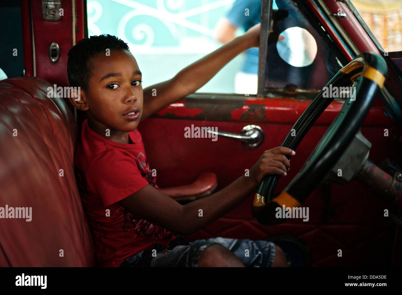 A Cuban boy sitting in a vintage American car in Old Havana. Stock Photo