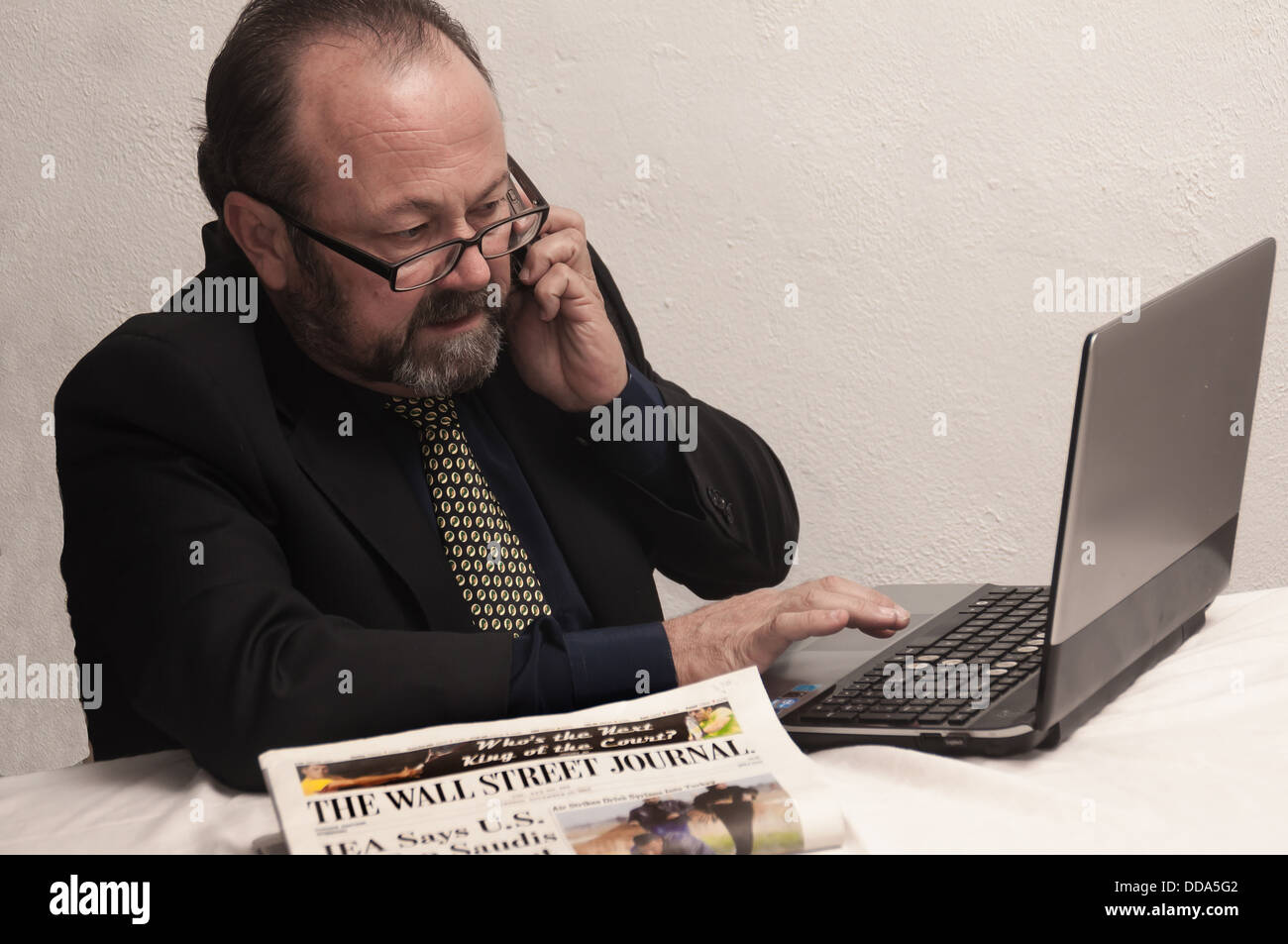 A businessman is using his laptop. He seems concerned, probably about business Stock Photo