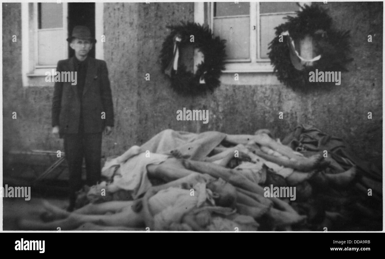 WWII Europe, Buchenwald, Germany, Concentration Camps, Man stands next to pile of dead bodies, Christmas wreaths in... - - 195357 Stock Photo