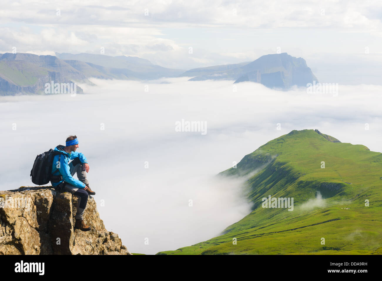 Hiker sitting on cliff, Mykines, Faroe Islands Stock Photo