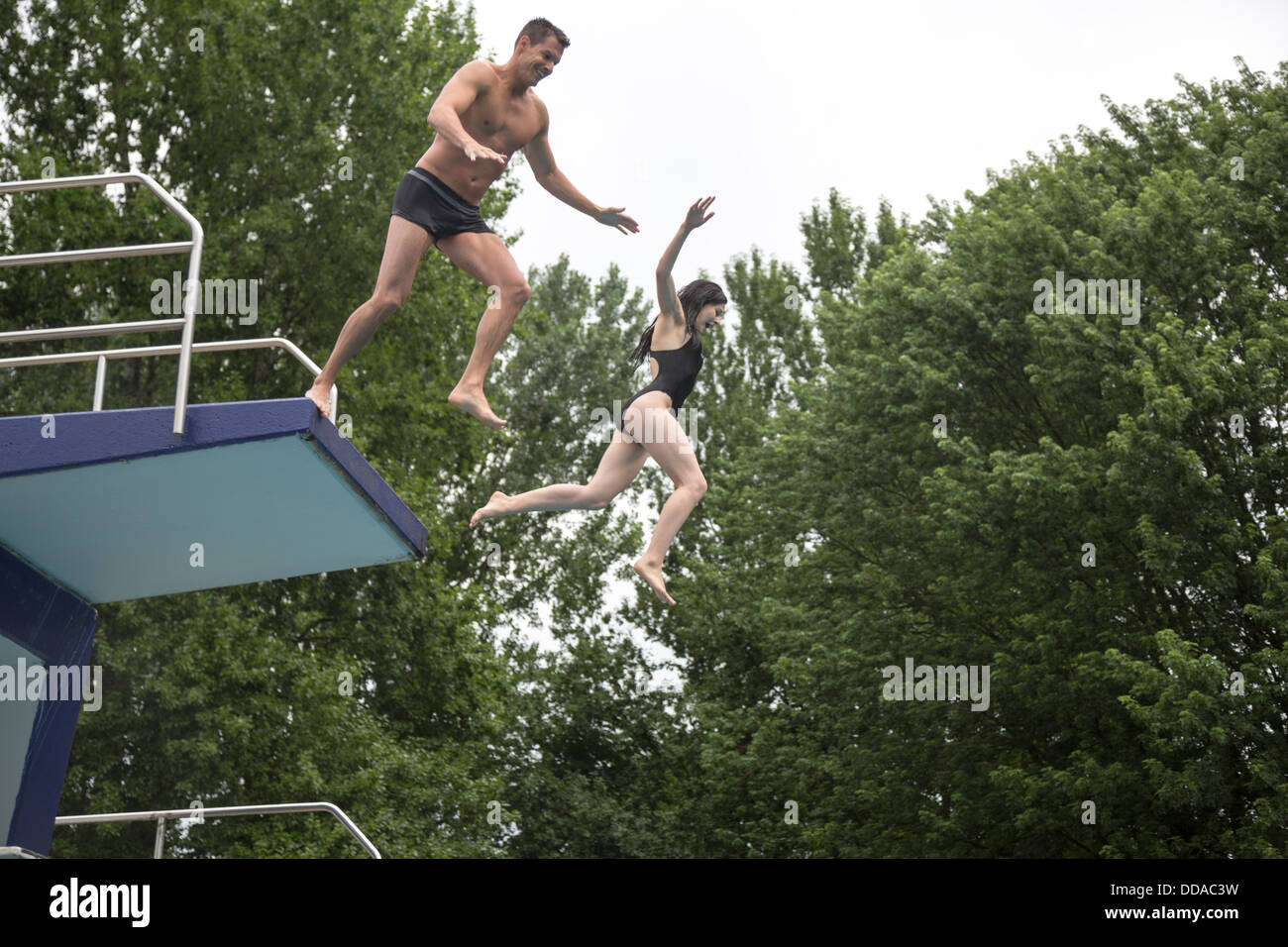 A couple jumping off a diving platform into a public swimming pool Stock Photo Alamy