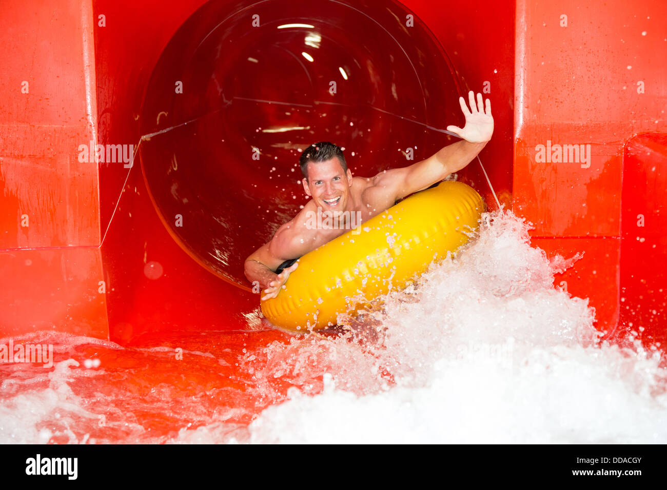 Man having fun in water slide at public swimming pool Stock Photo