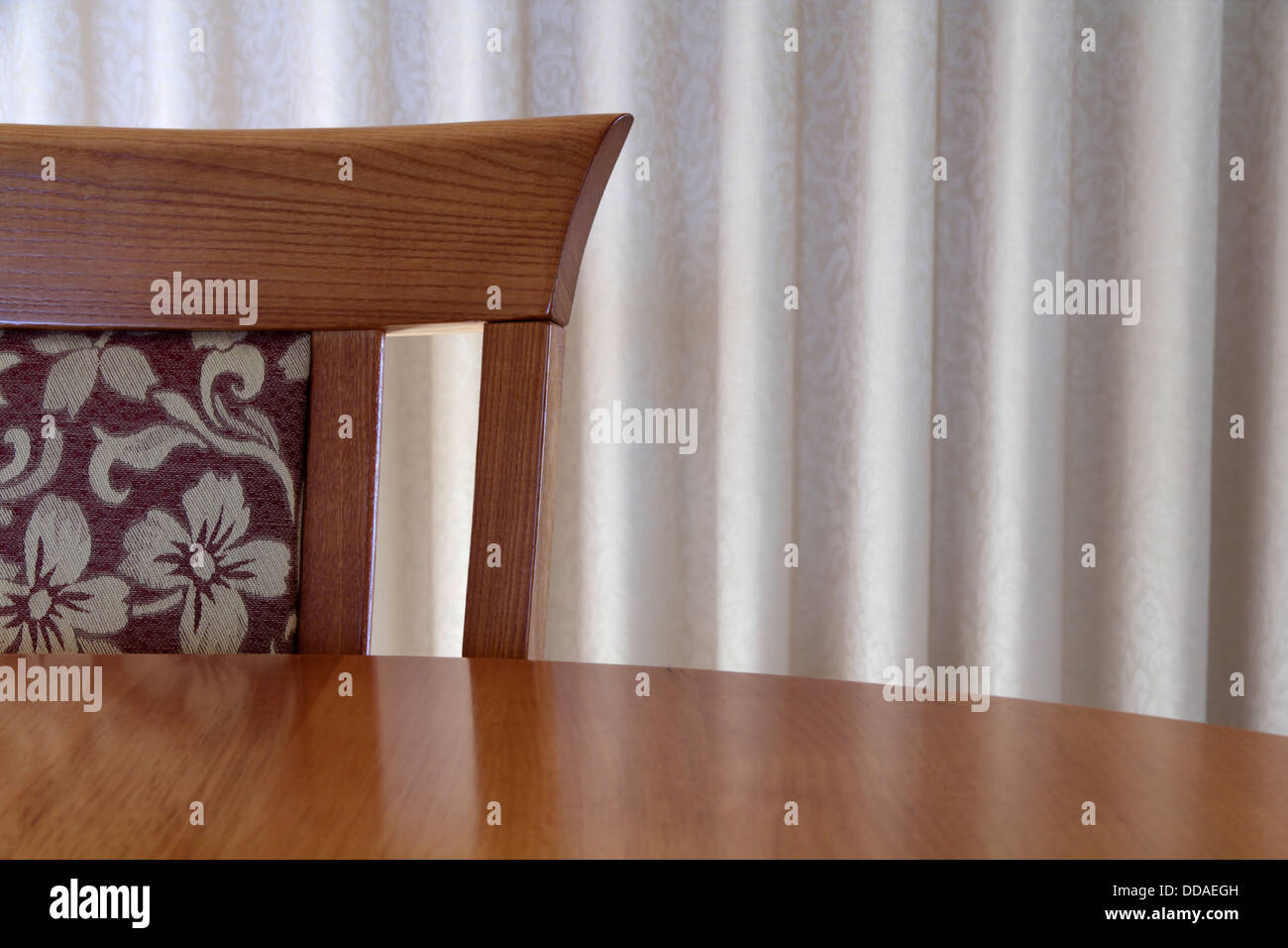 Interiors photo of a dining room chair at a curved timber table Stock Photo