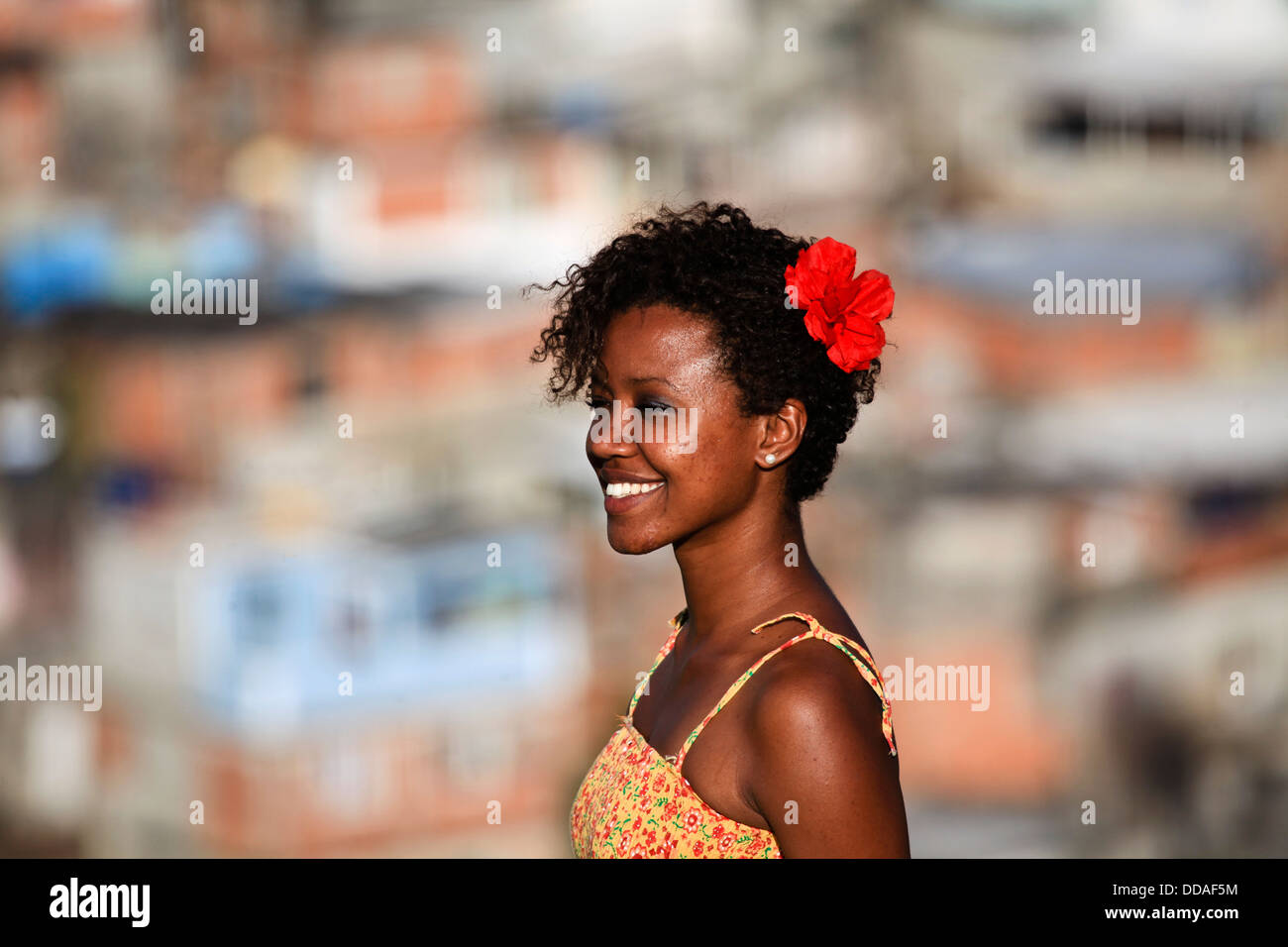 Beautiful black young woman with red flower on hair at Complexo do Alemão, Rio de Janeiro favela, Brazil. UPP since 2012 Stock Photo