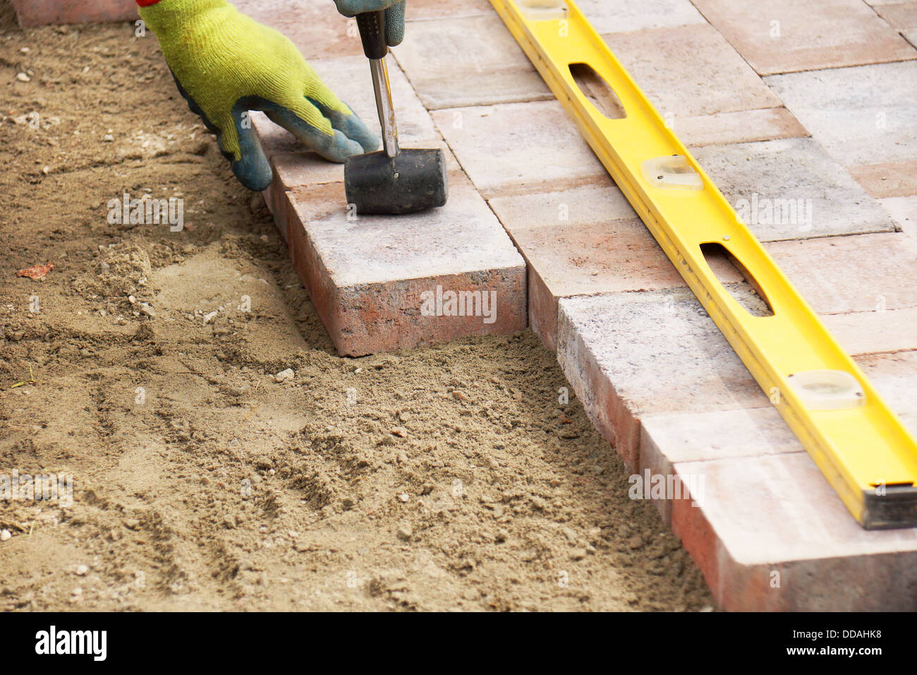 Installing paver bricks on patio, mallet to level the stones Stock