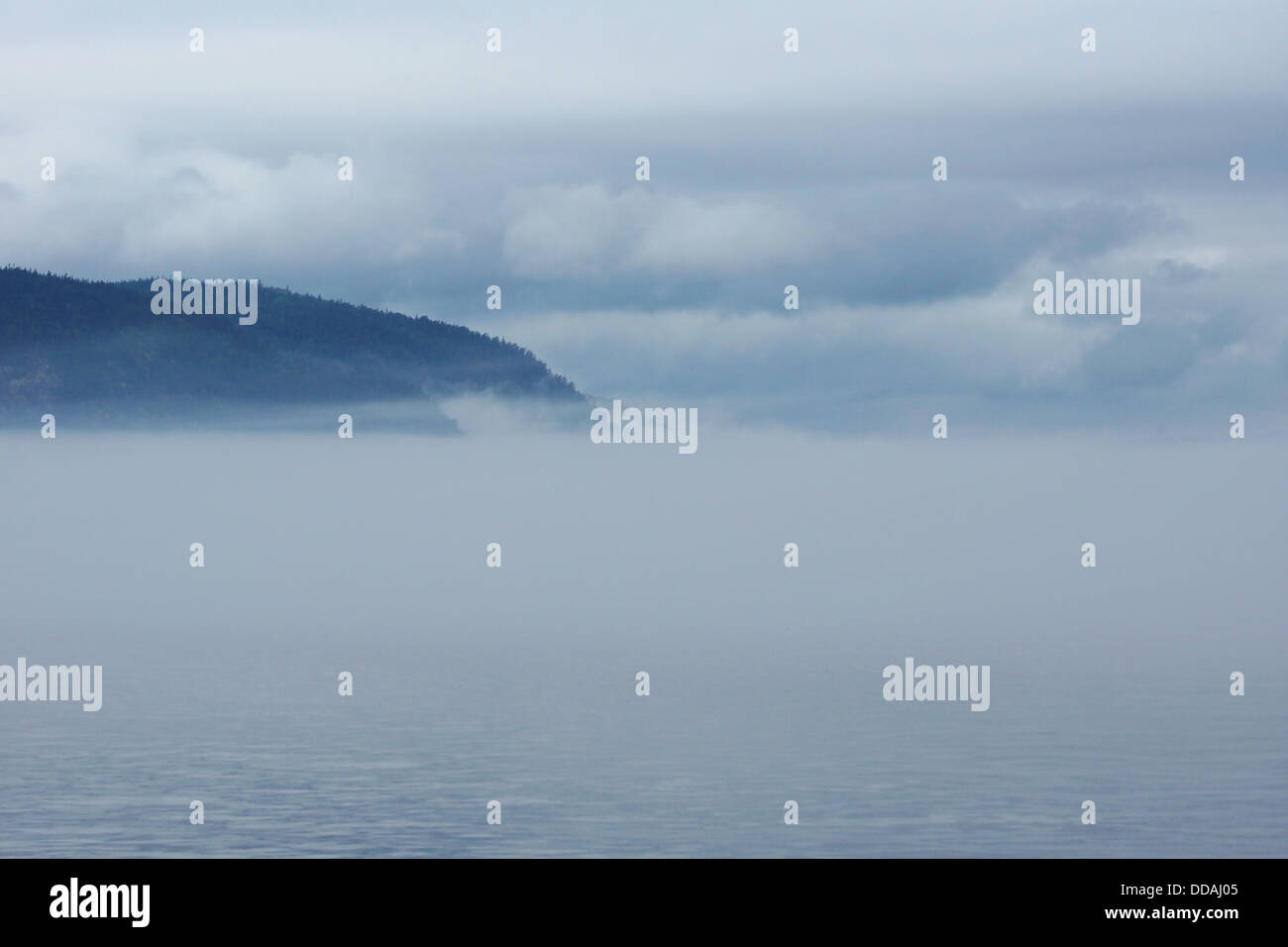 Thick fog over water with mountains and clouds, great landscape. Stock Photo