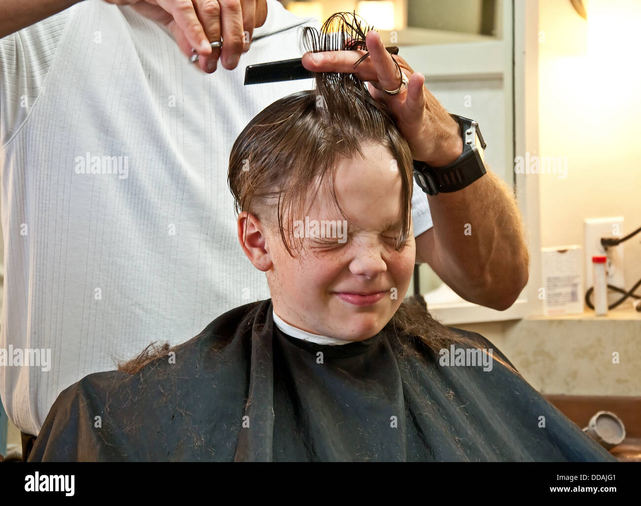 this 9 year old caucasian boy is getting his hair cut from