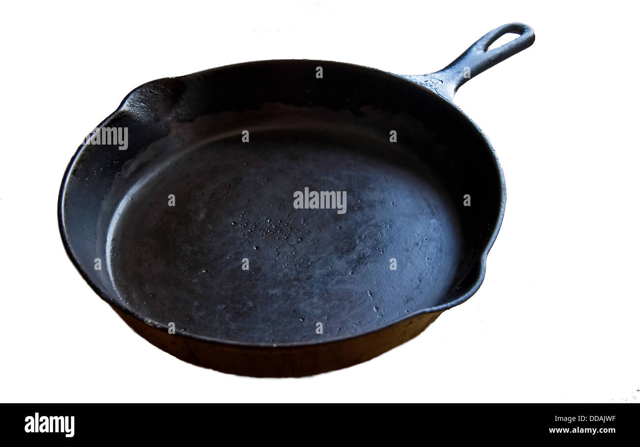 This is an old, black cast iron skillet, worn from many uses and age, isolated on a white background. Stock Photo