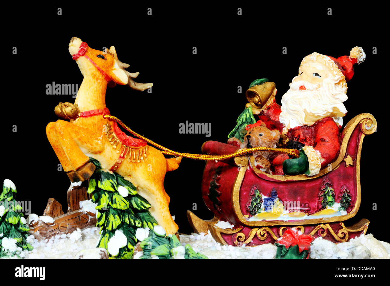 Ceramic Father Christmas in his sleigh with reindeer on a black background. Stock Photo
