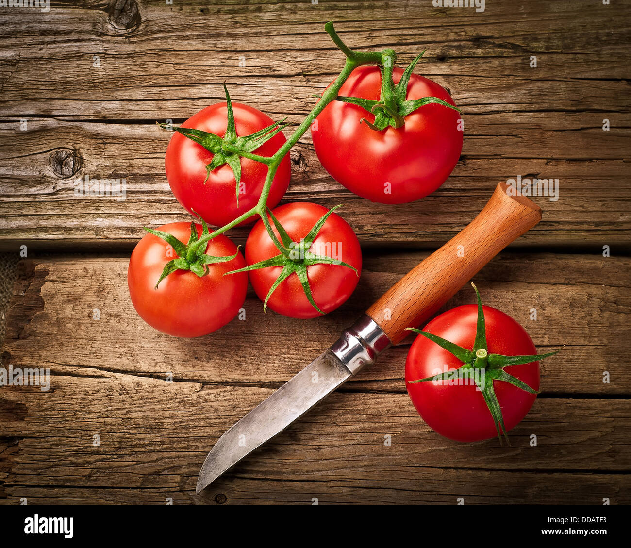 Fresh organic ripe tomatoes and steel knife on wooden table. Image in vintage style Stock Photo