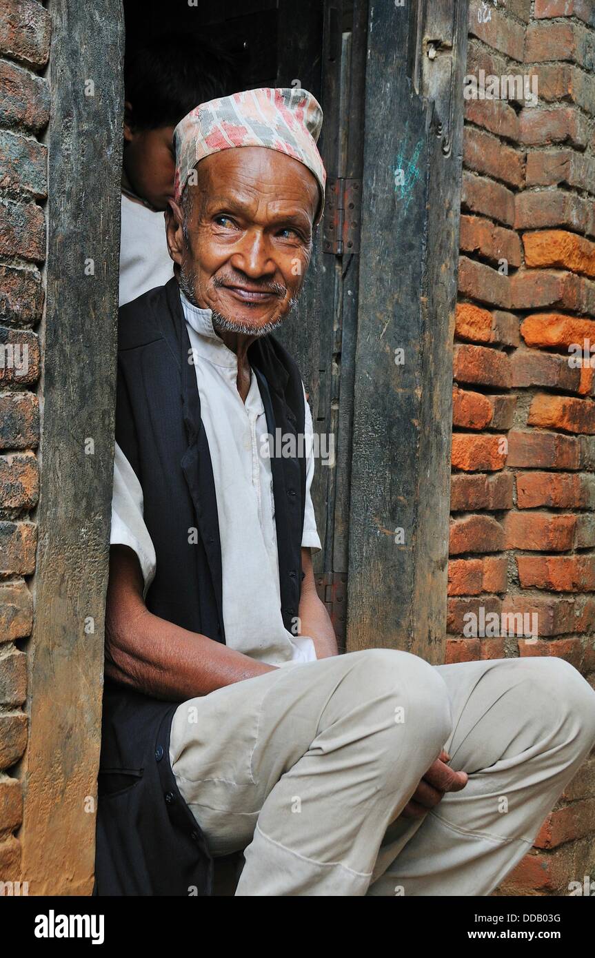 Old man sitting at the entrance of his house in the quietness Stock Photo