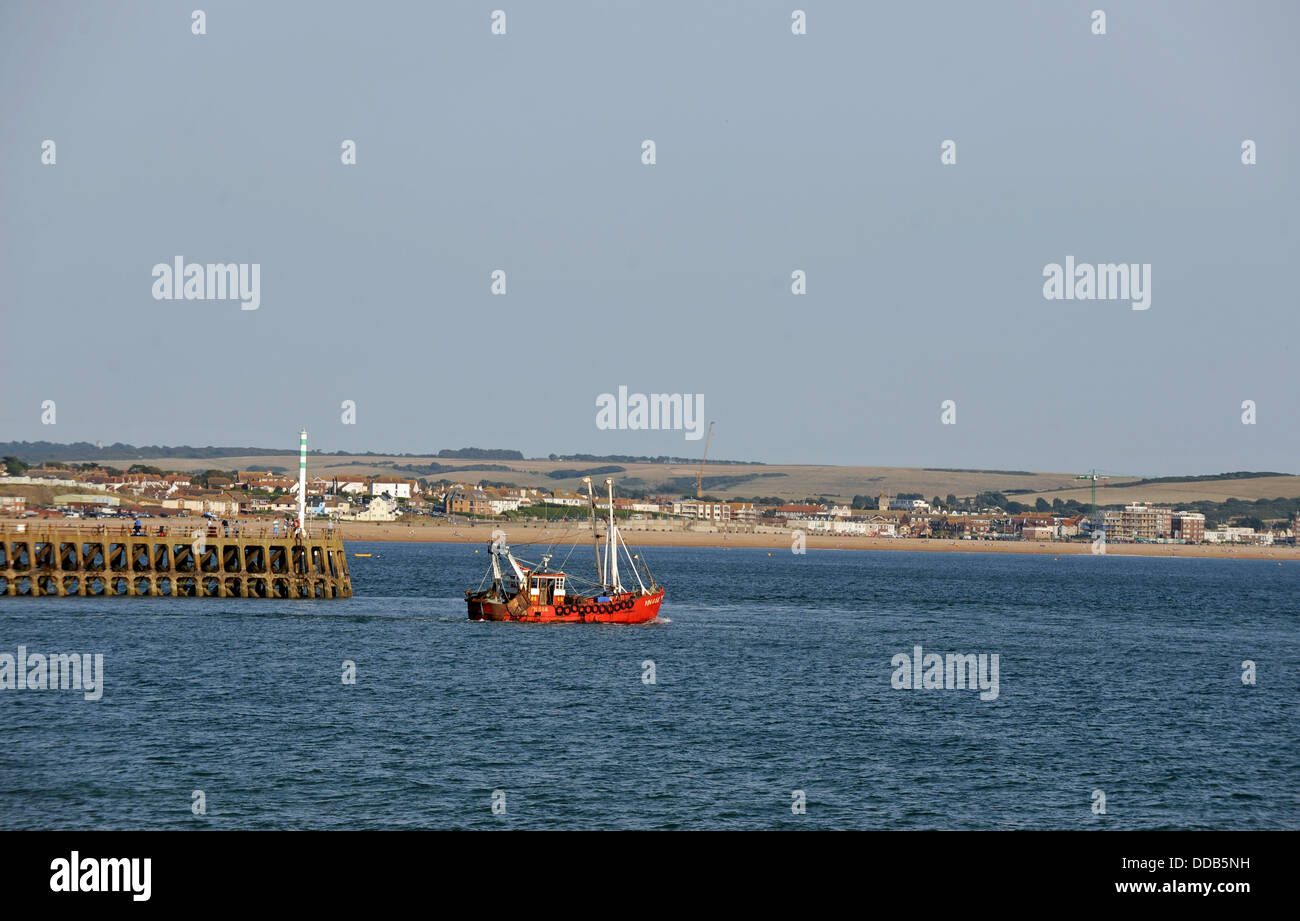 Fishing boat heads out to sea from the entrance of Newhaven Harbour East Sussex UK Stock Photo