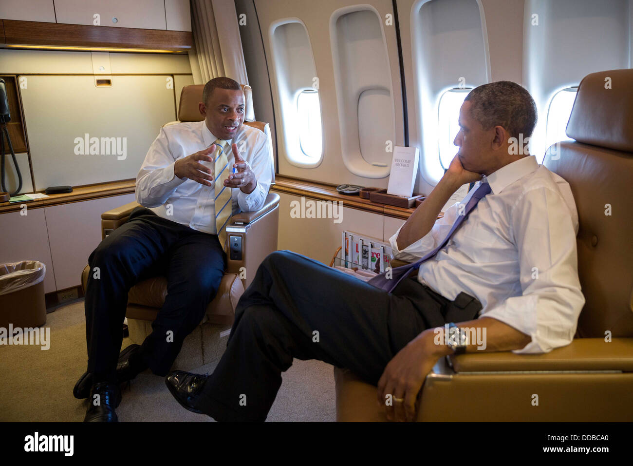 US President Barack Obama talks with Transportation Secretary Anthony Foxx aboard Air Force One during the flight to Jacksonville, Florida July 25, 2013. Stock Photo