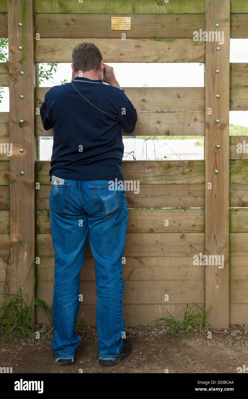 Wildlife observation. Bird watcher watching birds and other wildlife through a screen at Attenborough Nature Reserve, Nottinghamshire, England, UK Stock Photo