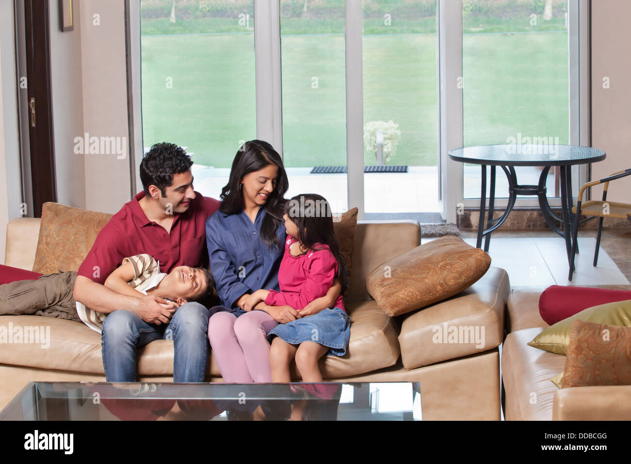 Young parents sitting with kids on sofa at home Stock Photo