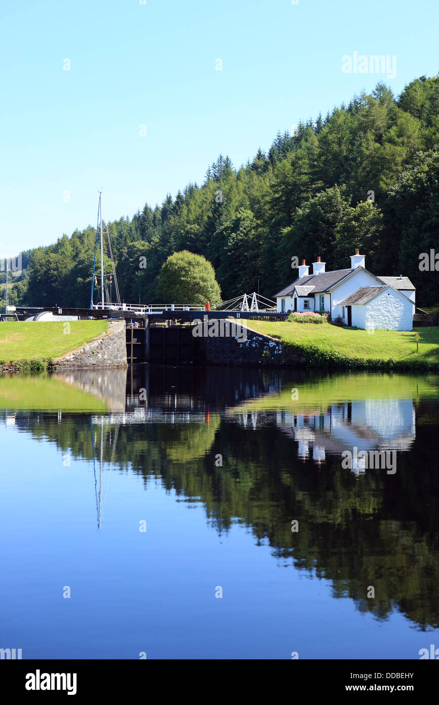 Lock keepers cottages reflected in a still Crinan Canal at Dunardry Bridge in Argyll, Scotland Stock Photo