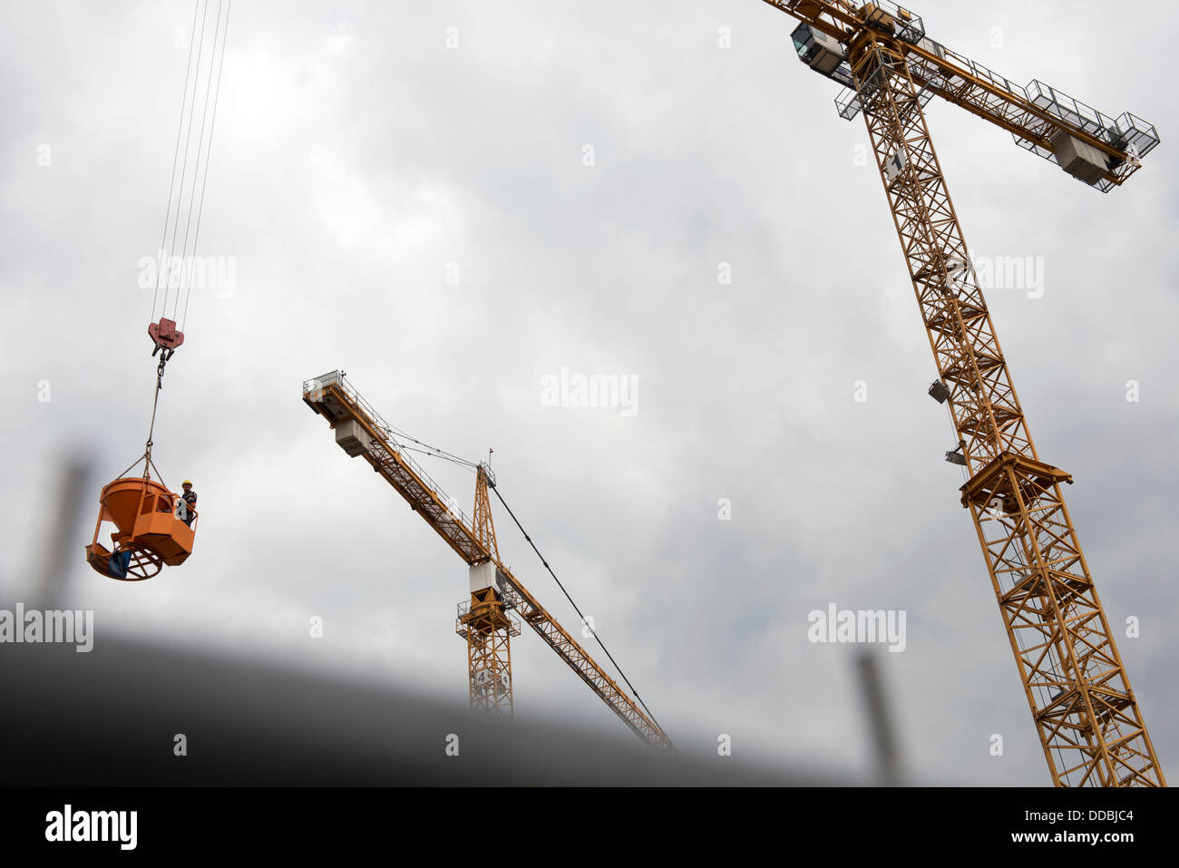 Tower crane lifting a workman operating a bucket carrying wet concrete