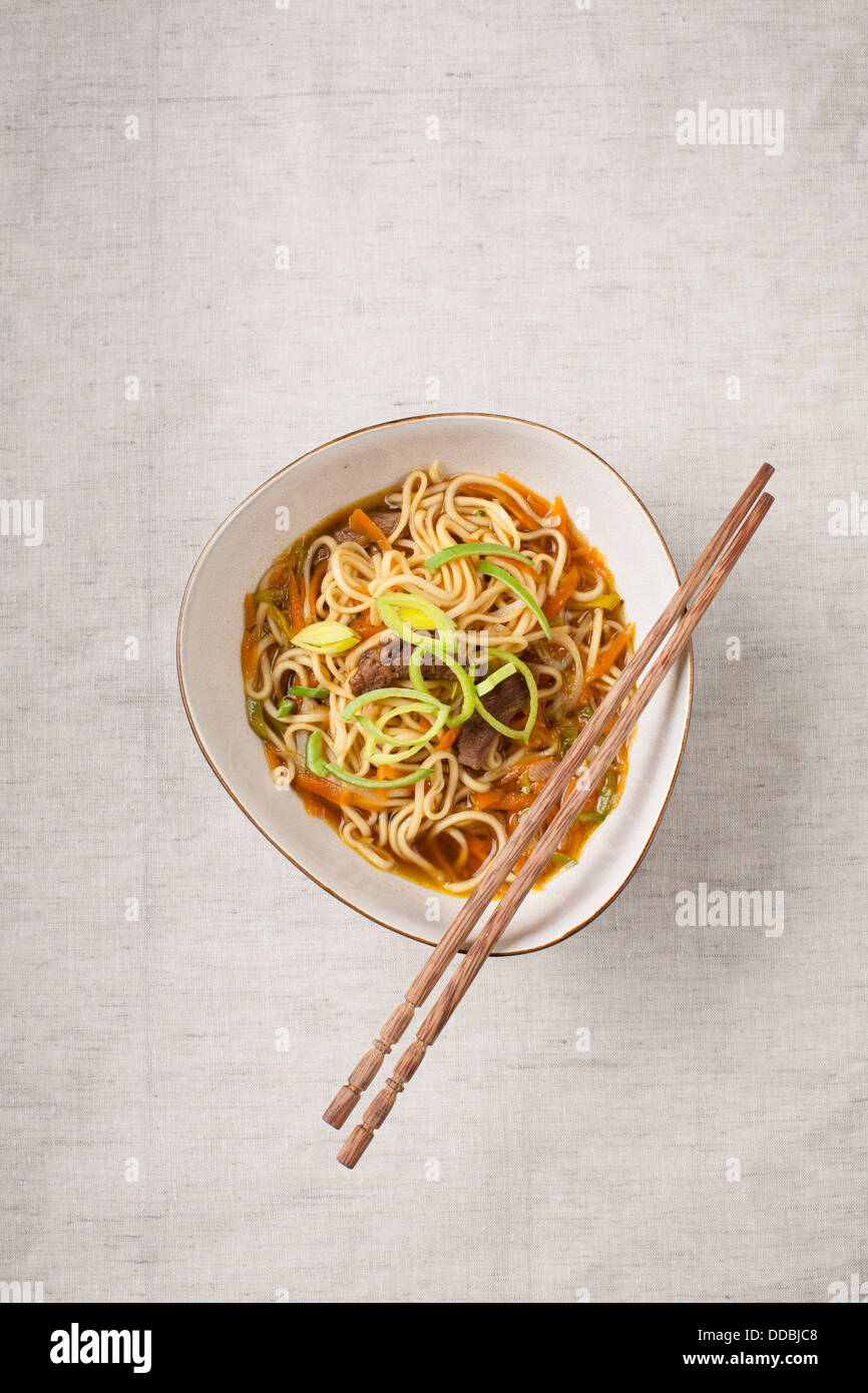 Asian noodles with pork and vegetables on textile background Stock Photo