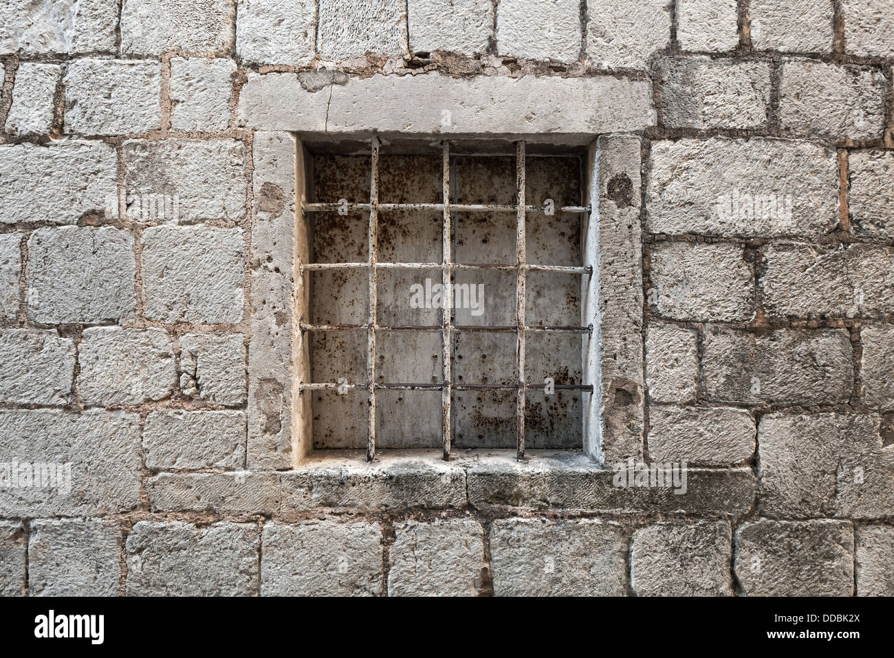 Locked ancient stone prison wall with metal window bars Stock Photo