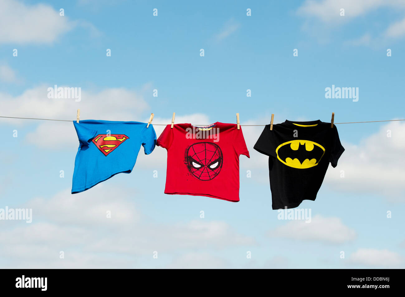 Childs superman, batman and spiderman t shirts hanging on a washing line Stock Photo