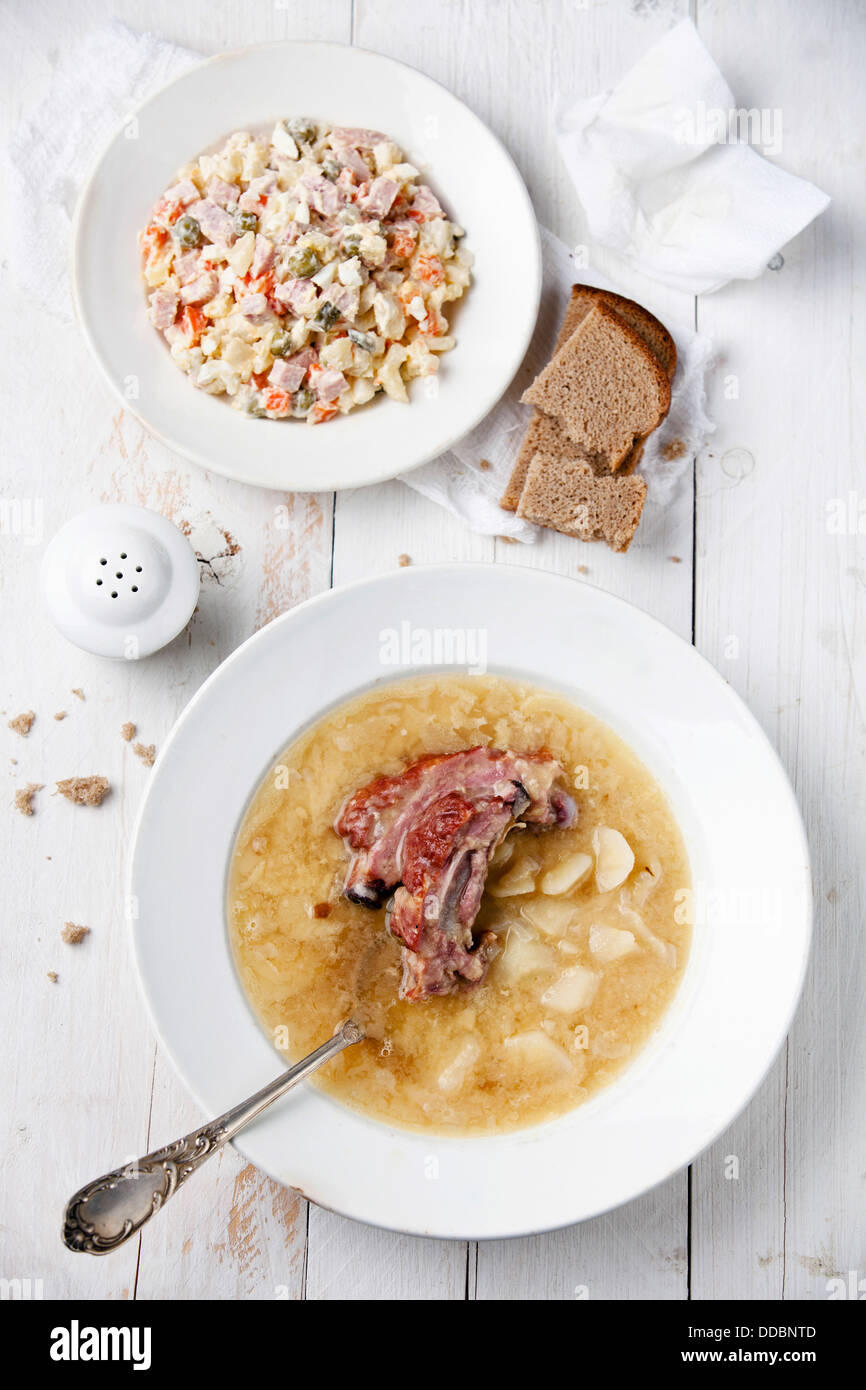 Russian traditional salad olivier and Pea soup with bread and smoked ribs Stock Photo