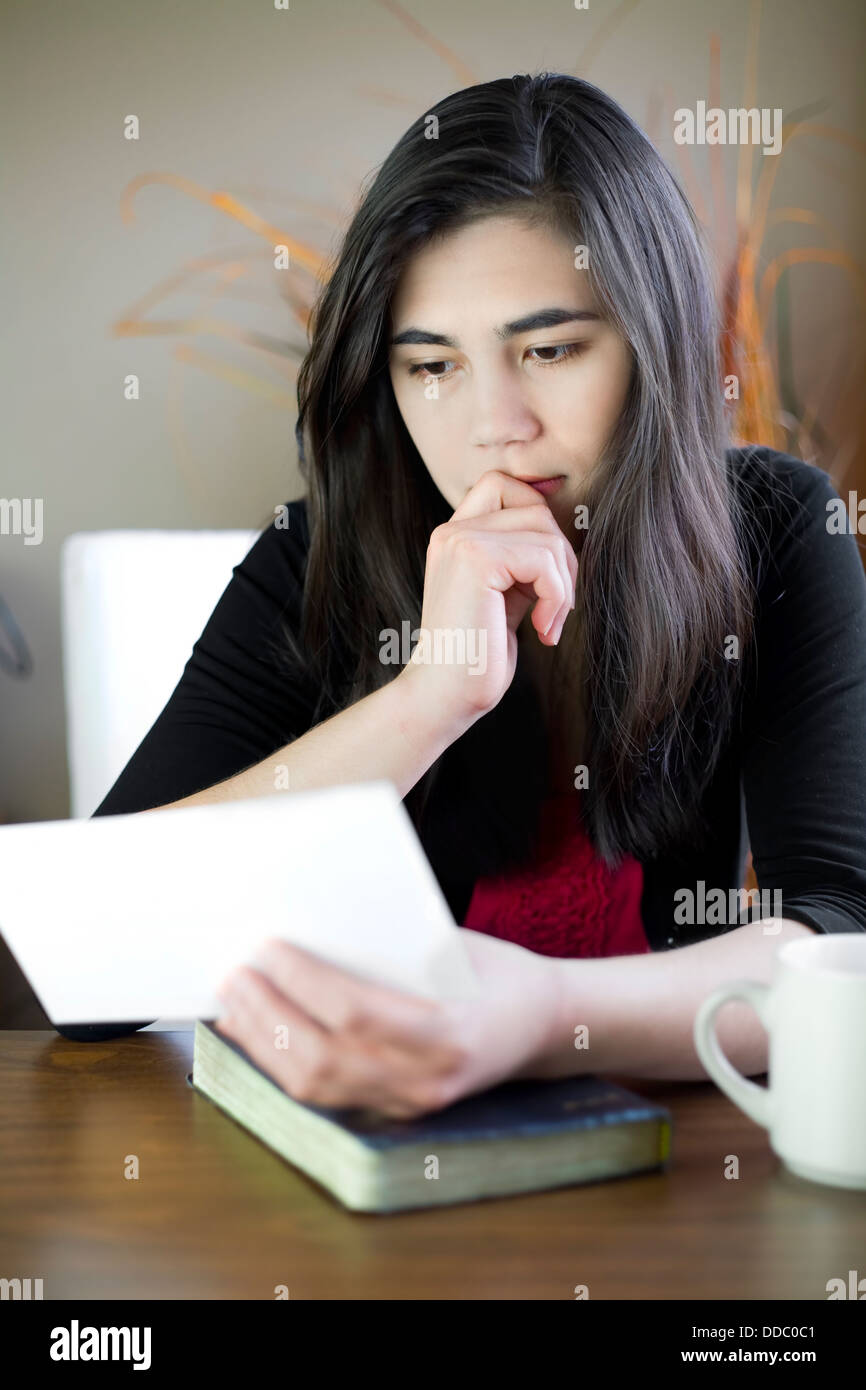 Teenage girl or young woman reading a note, worried expression Stock Photo