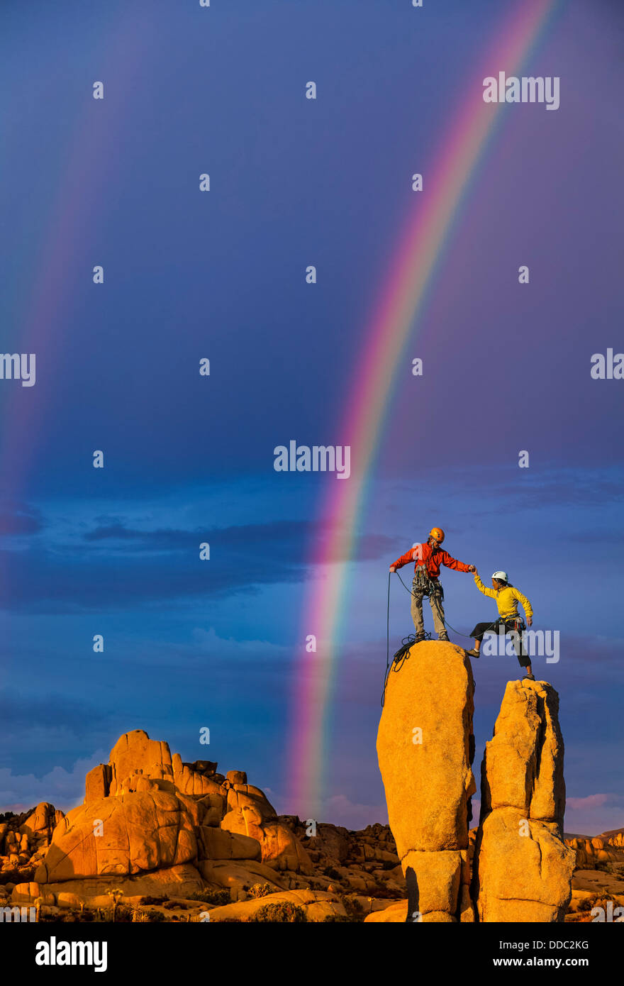Team of climbers conquer the summit of a challenging rock spire. Stock Photo