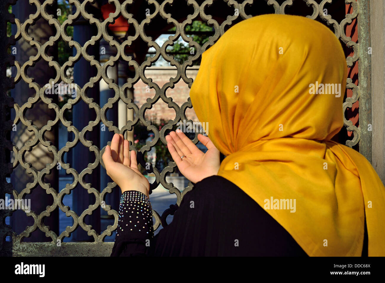 veiled woman praying in front of the old tombstones Stock Photo