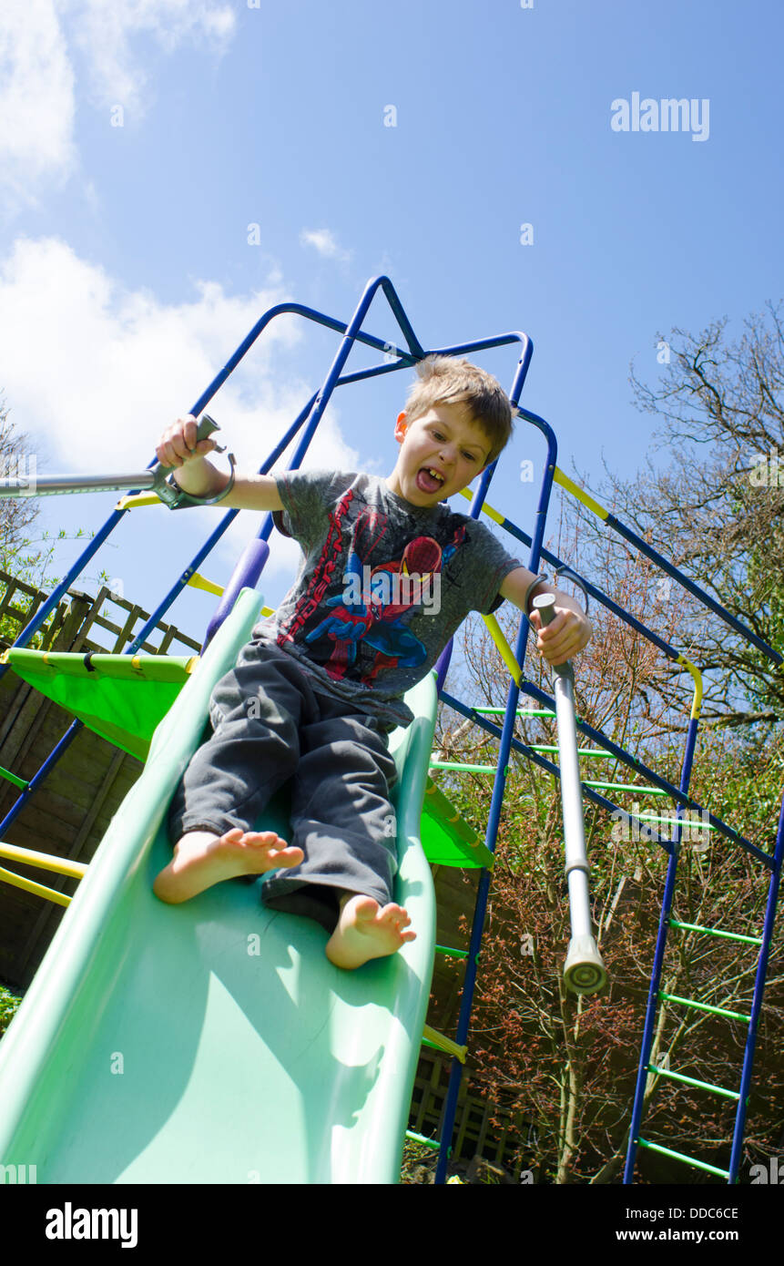 eight year old boy with crutches being adventurous by sliding down a
