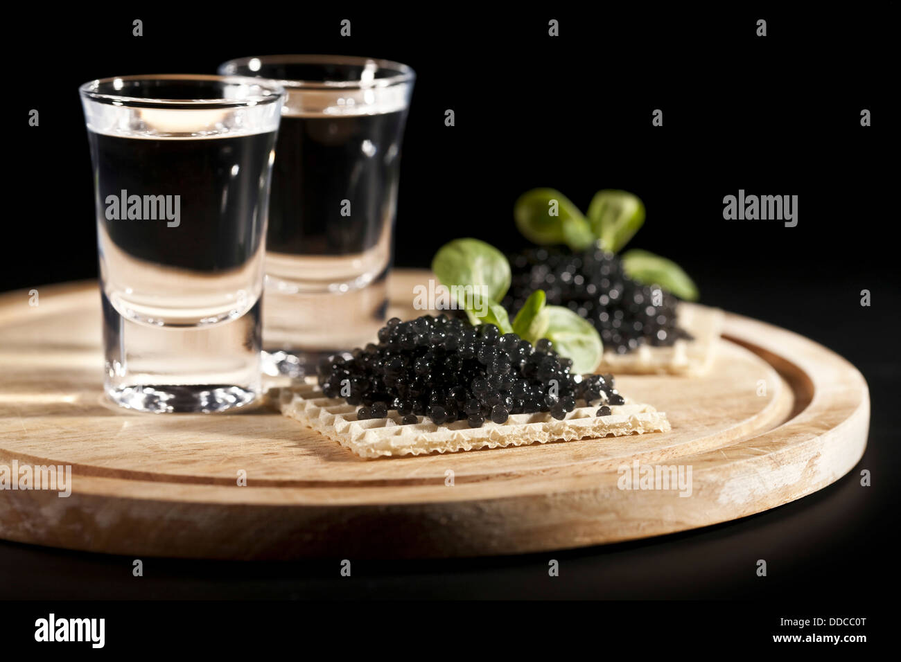 served place setting: vodka and sandwiches with black caviar on black background Stock Photo