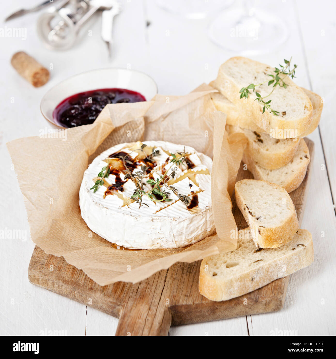Baked Camembert cheese with thyme and toasted bread on wooden board Stock Photo