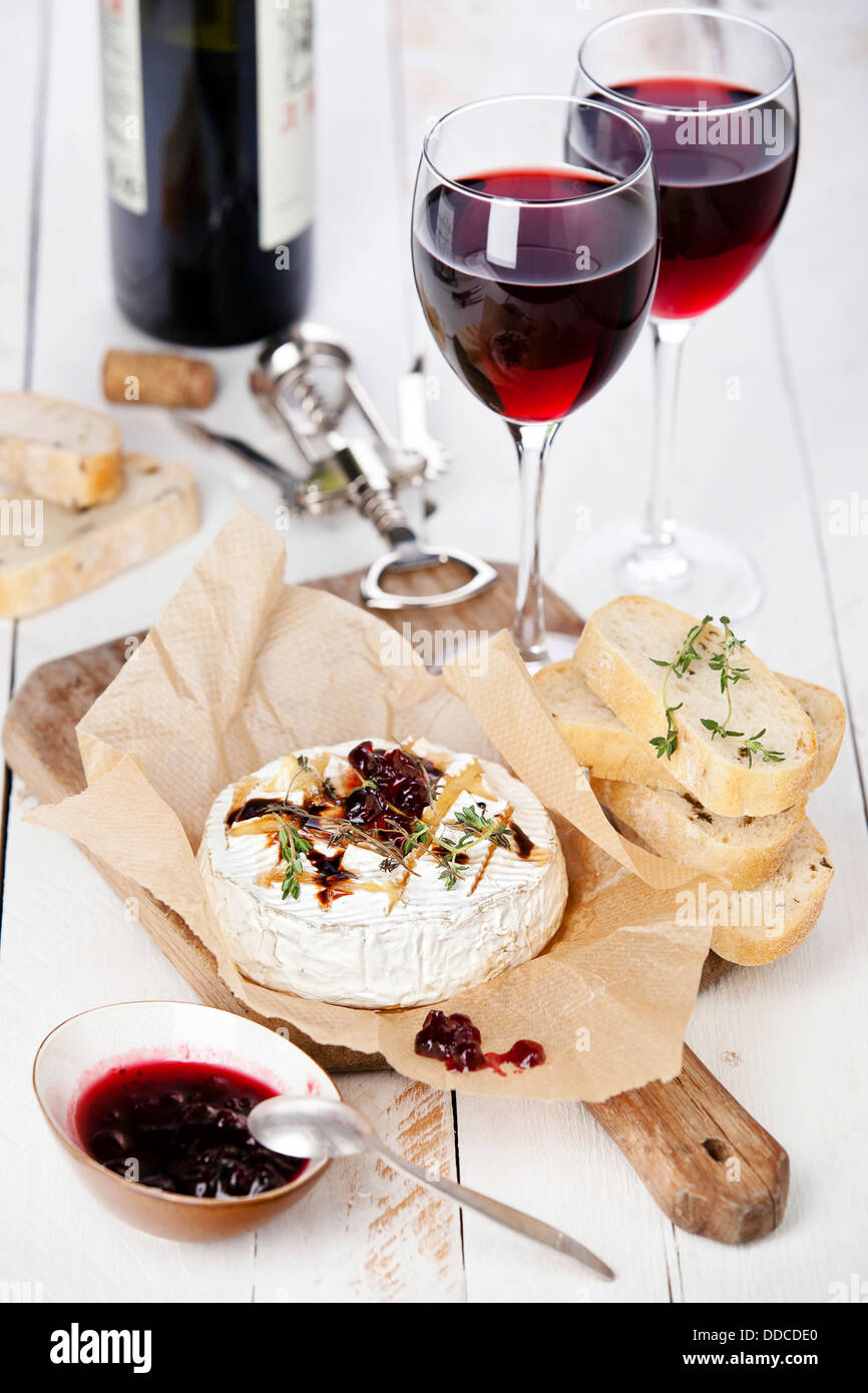 Baked Camembert cheese with red wine and toasted bread on wooden board Stock Photo