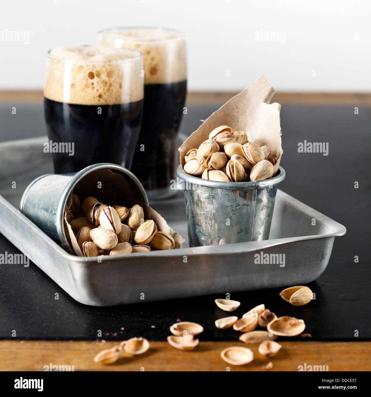 Dark beer and pistachios at textured table Stock Photo