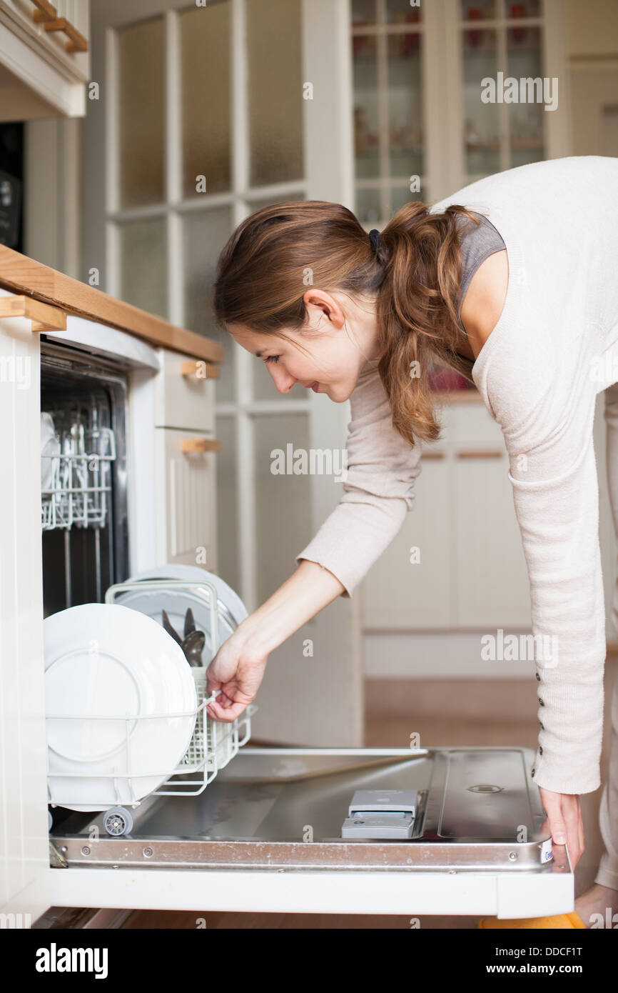 Housework: young woman putting dishes in the dishwasher Stock Photo