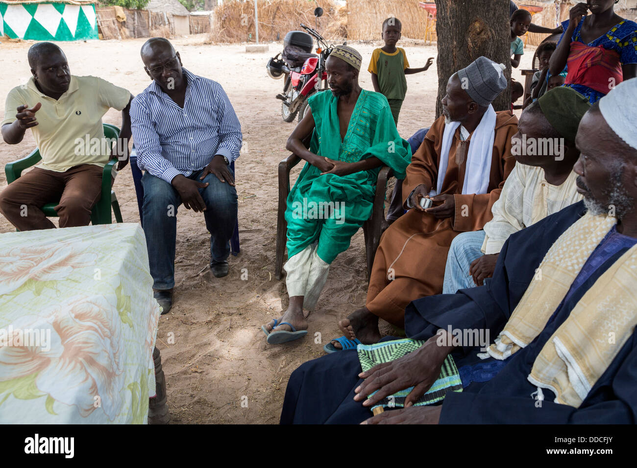 Men from Non-profit NGO (in western dress) Speak to Men at Microcredit Meeting, Djilor, a Wolof Village, near Kaolack, Senegal. Stock Photo