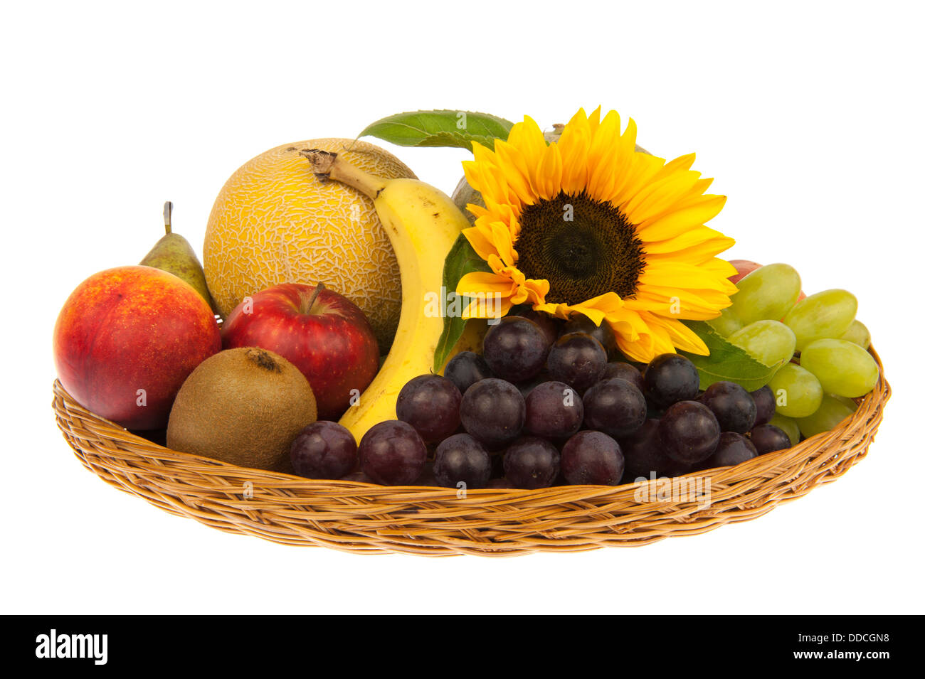 Basket with banana, apple, nectarine, peach, kiwi, pear, melons, green and blue grapes decorated with sunflower Stock Photo