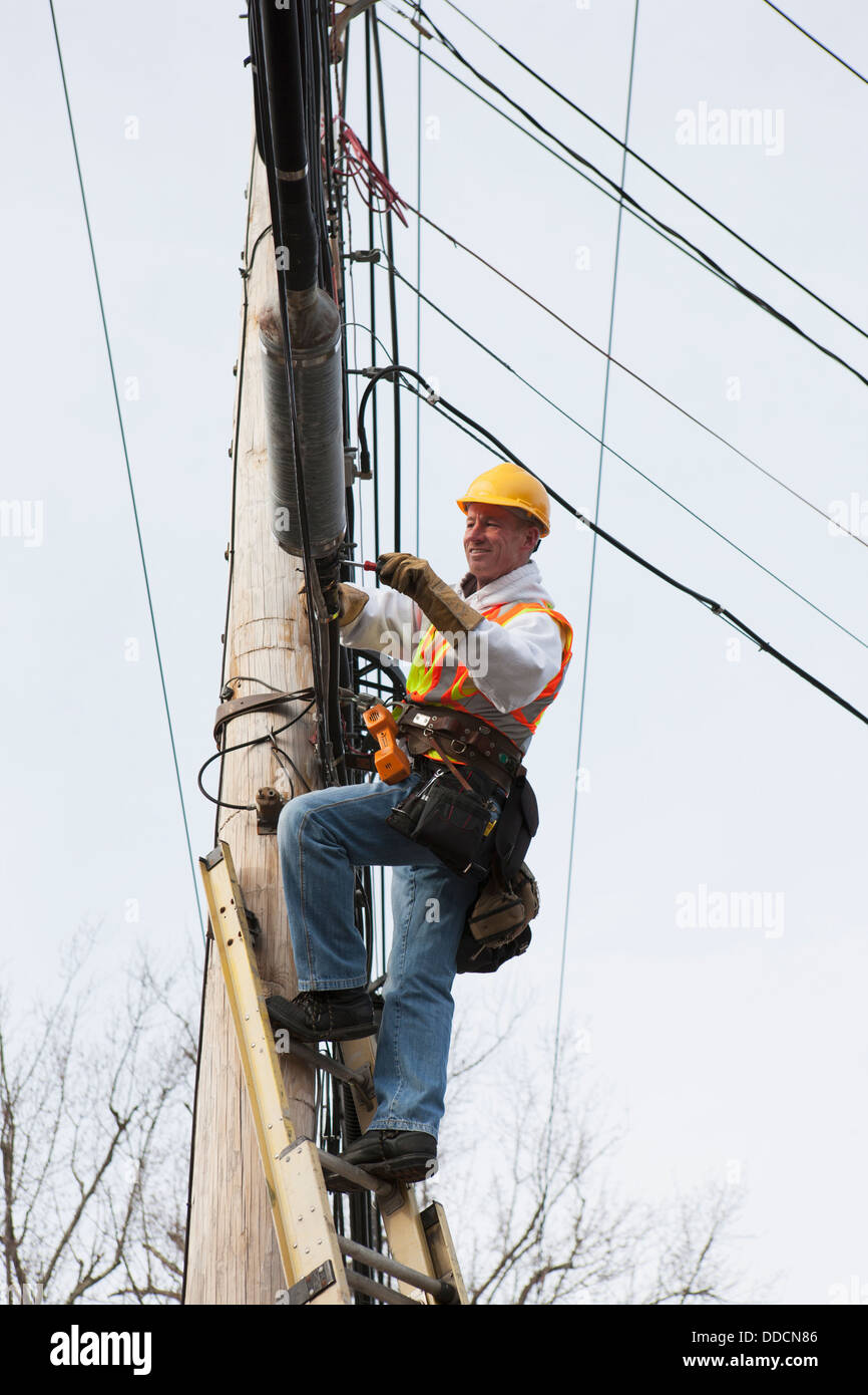 Communications worker attaching clamps to new cable bundle on power