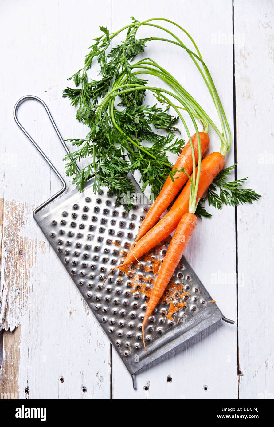 Fresh carrots with grater on white wooden background Stock Photo