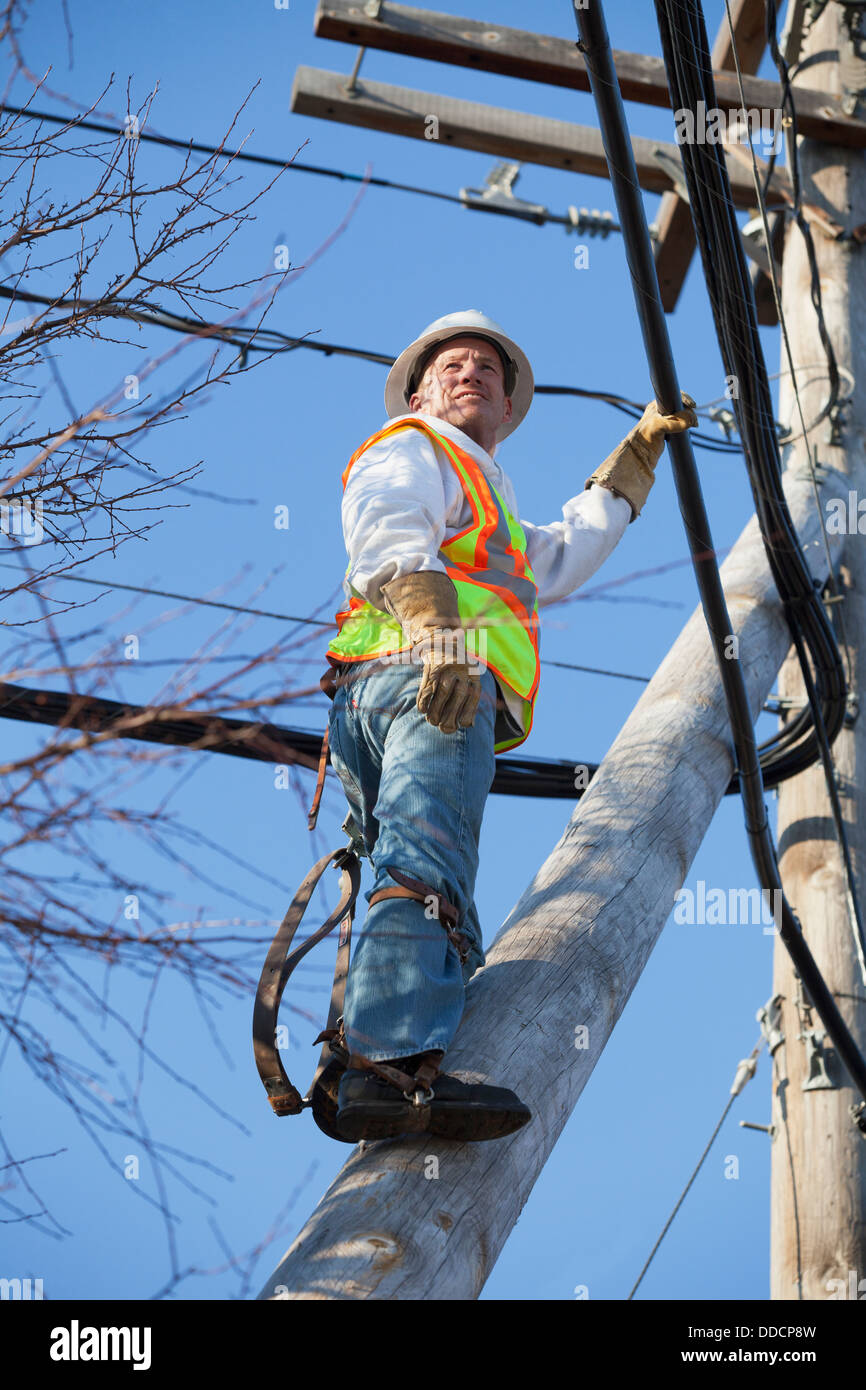 Cable lineman climbing a pole brace to cable bundles on power pole