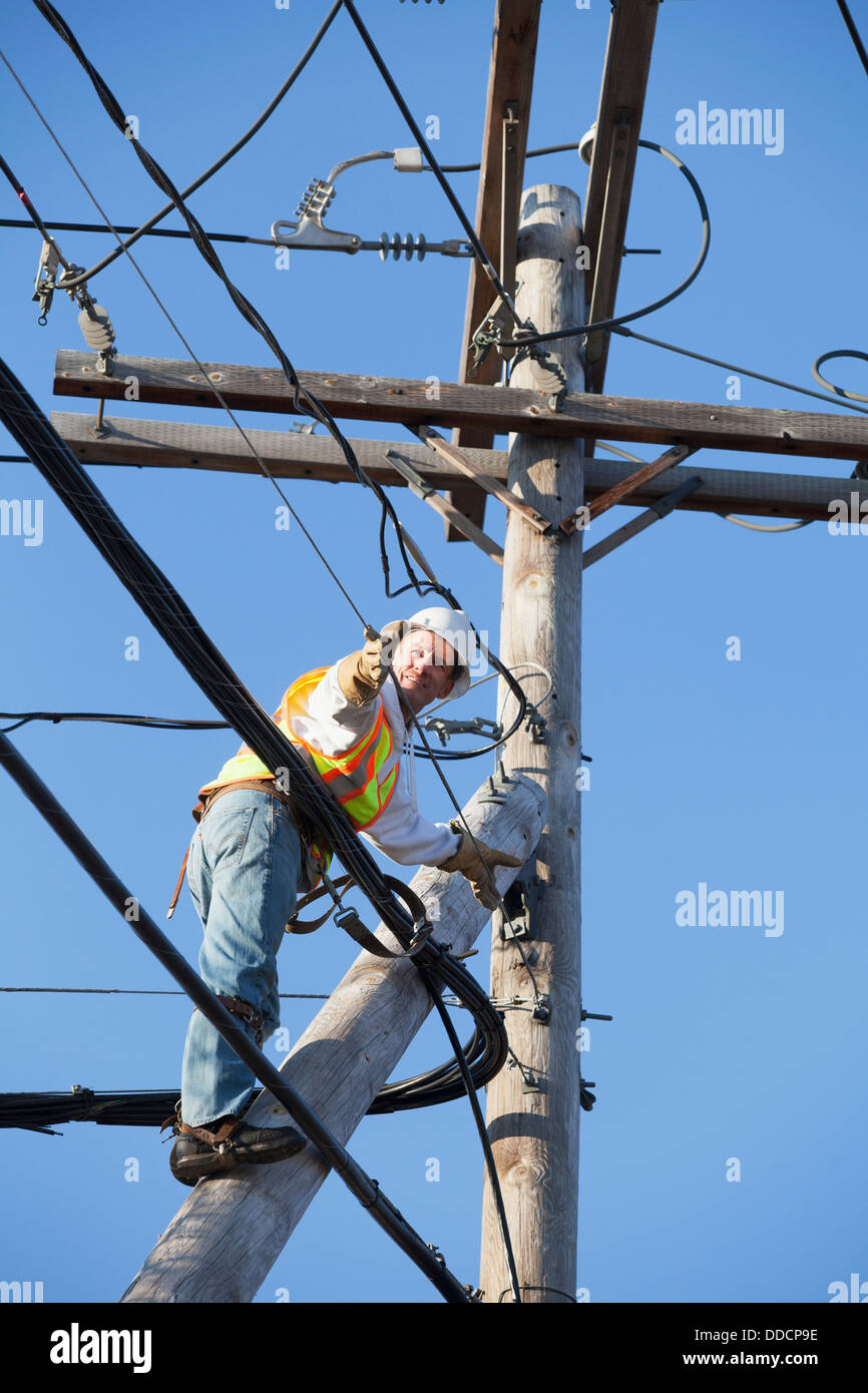 Cable lineman installing new suspension wire from power pole brace ...