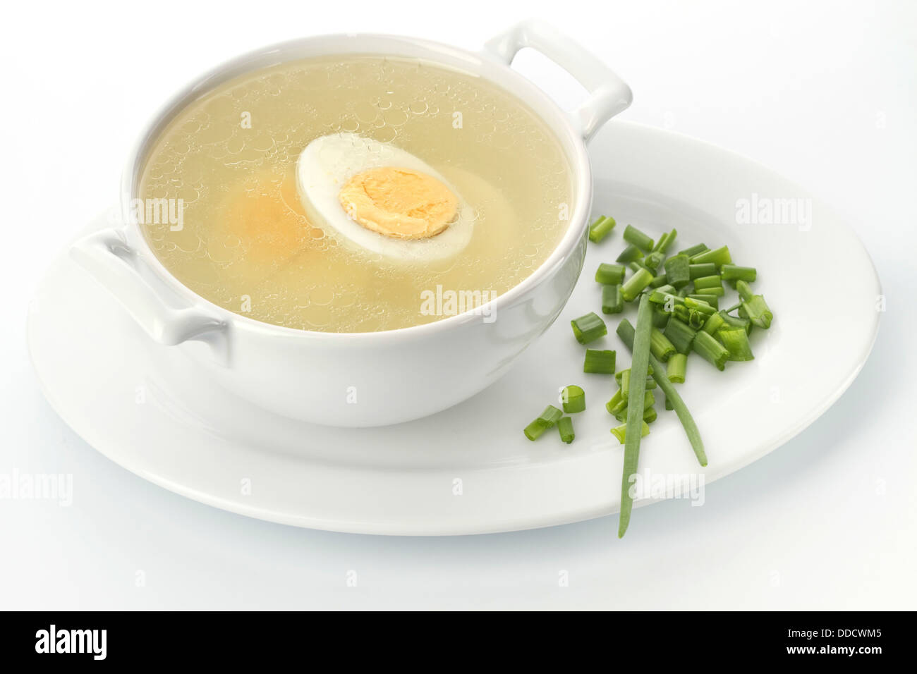 Served place setting with chicken broth and chives Stock Photo