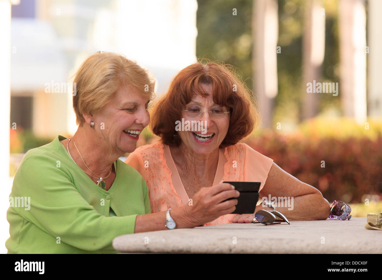 Senior friends looking at a smart phone and smiling Stock Photo